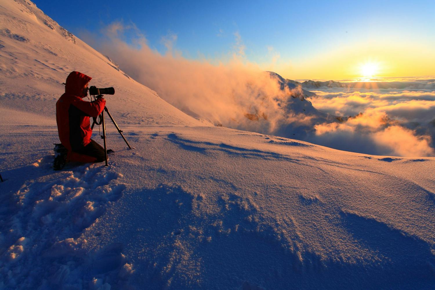 Mann fotograferer soloppgangen på fjellet.